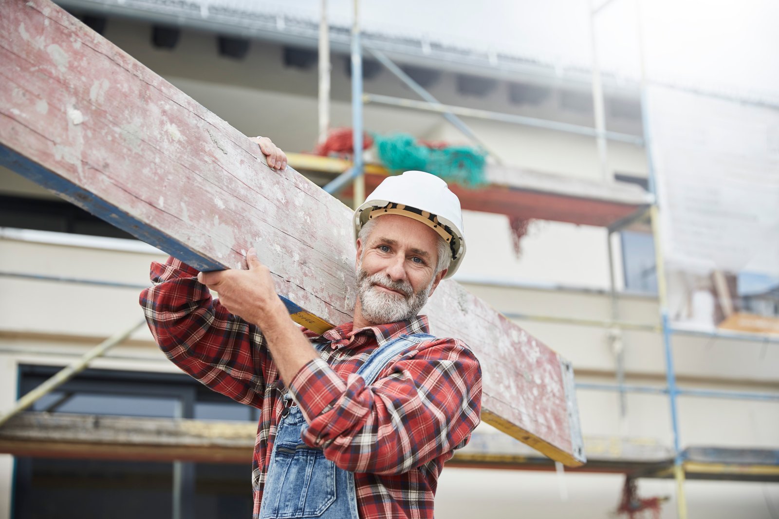 Ein Arbeiter trägt ein Brett zur Baustelle | Zurich Rohbauversicherung