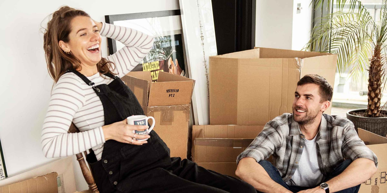 Ein Pärchen packt freudig Umzugskartons aus