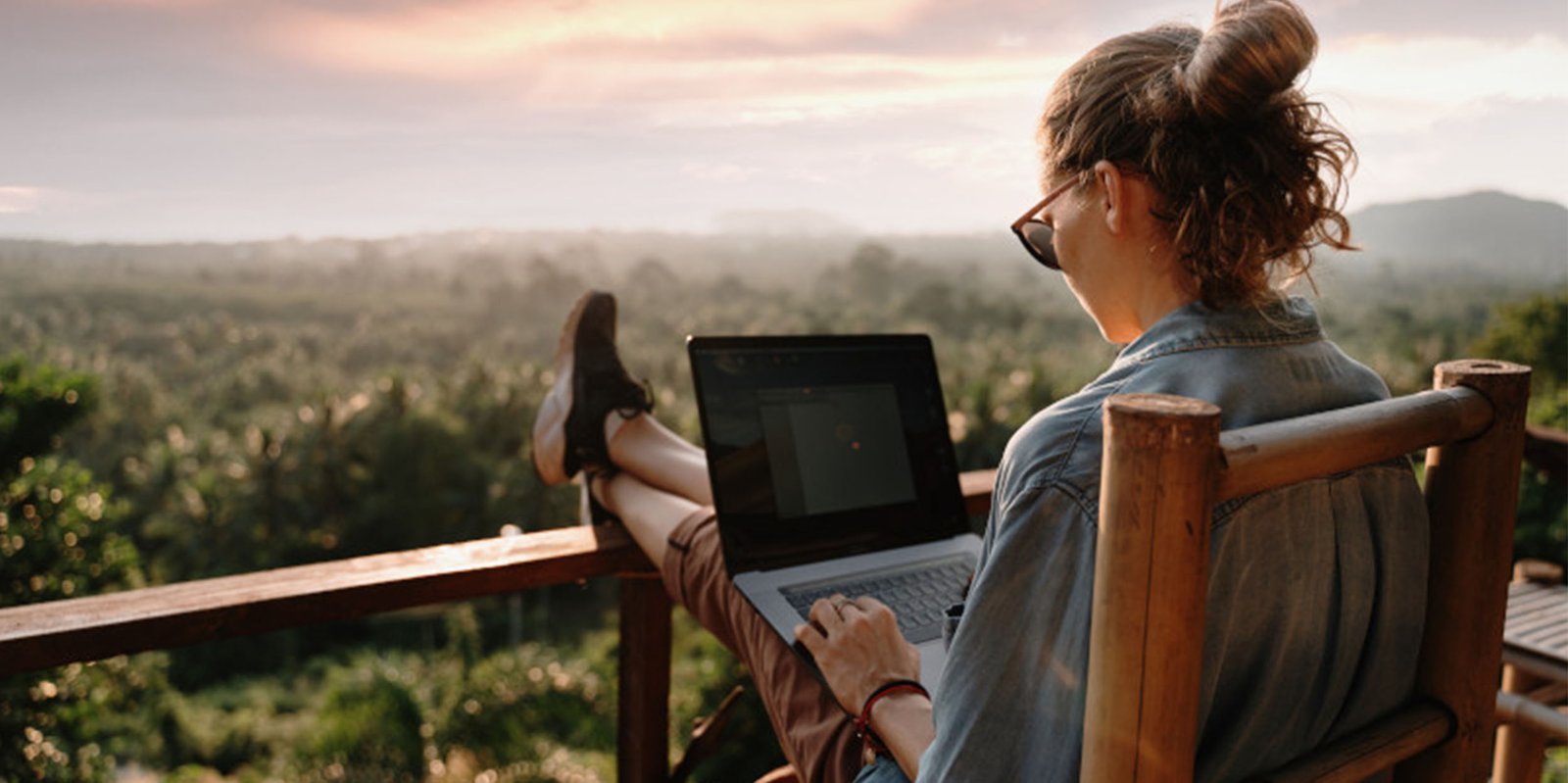 Eine Dame sitz im Urlaub am Laptop und schließt eine Versicherungab