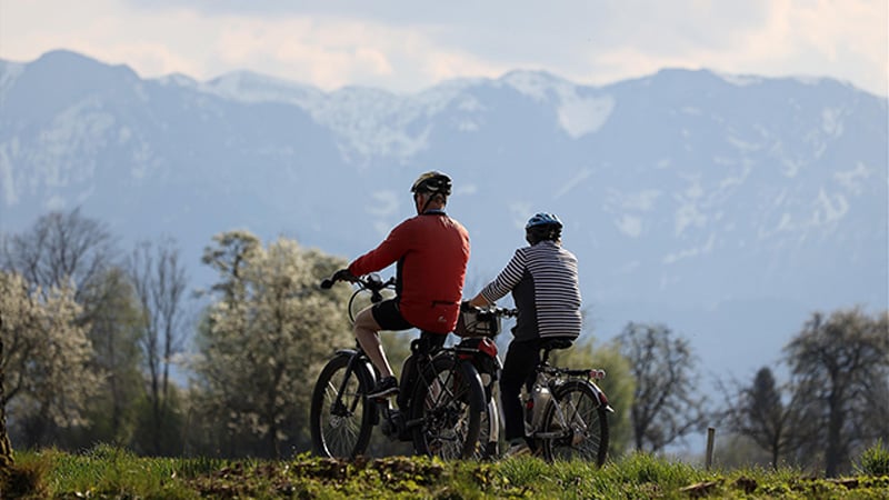 Ein älteres Pärchen fährt mit E-Bikes in den Bergen