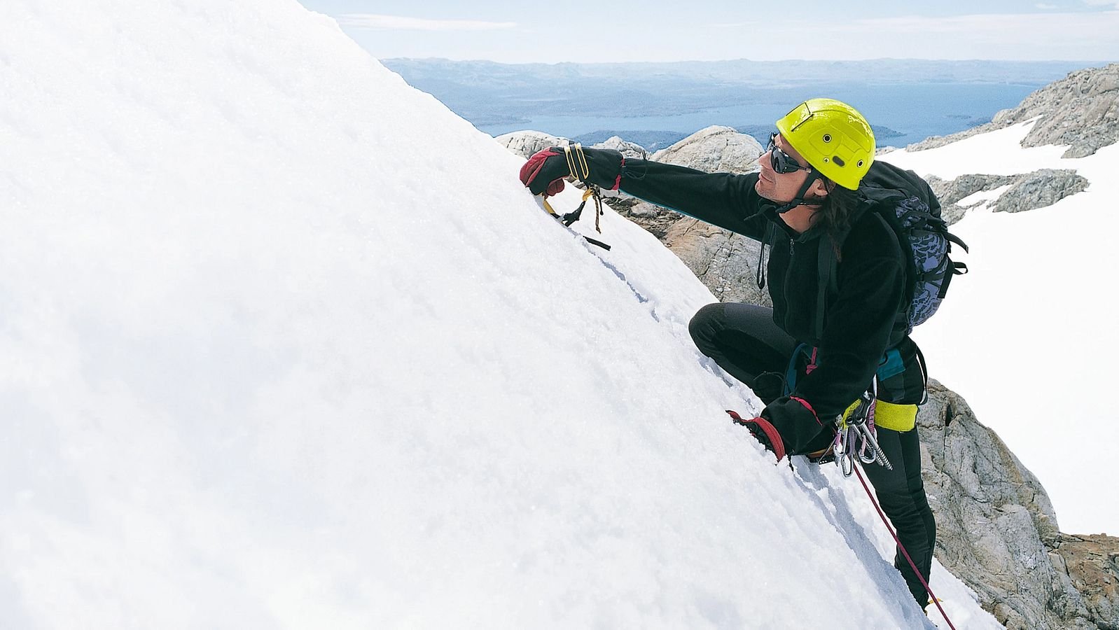 Mann geht mit Steigeisen am steilem Hang.