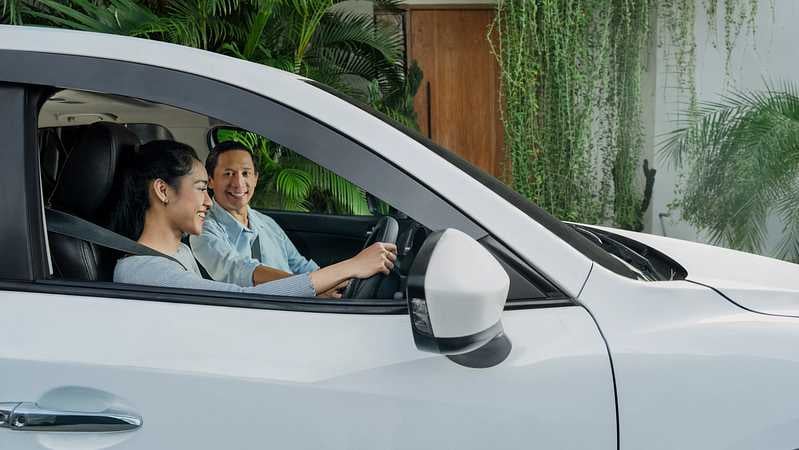 Ein Vater und seine Tochter machen eine Probefahrt in einem weißem Auto.