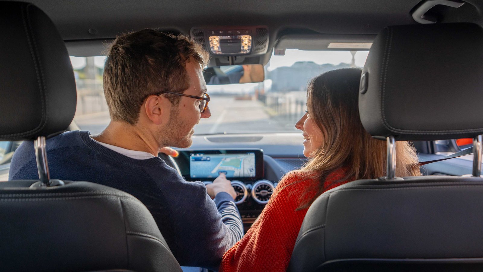 Eine Mann und eine Frau sitzen im Auto und unterhalten sich lächelnd