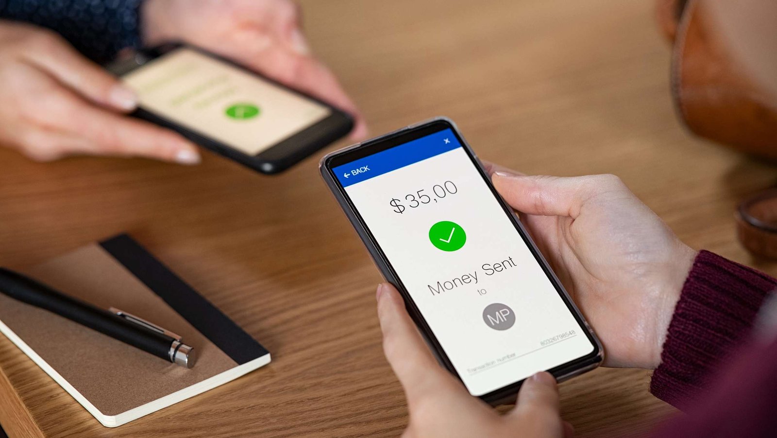 Geld wird über ein Handy an eine zweite Person gesendet, man sieht die erfolgreiche Transaktion am Handy.