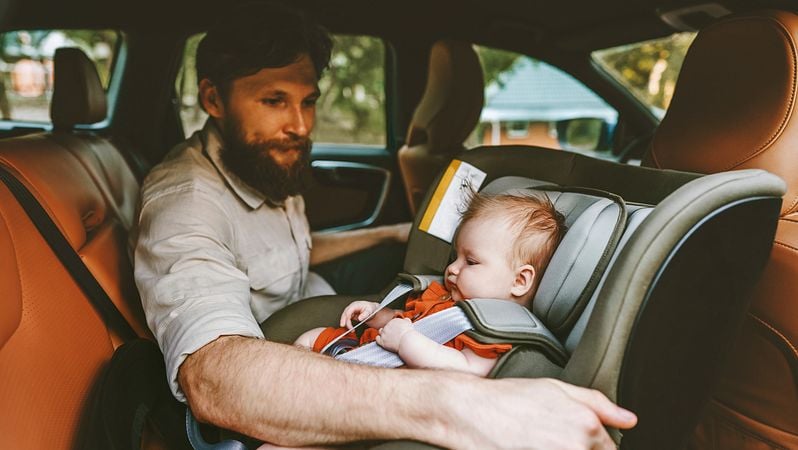 Mann schnallt Baby im Auto an