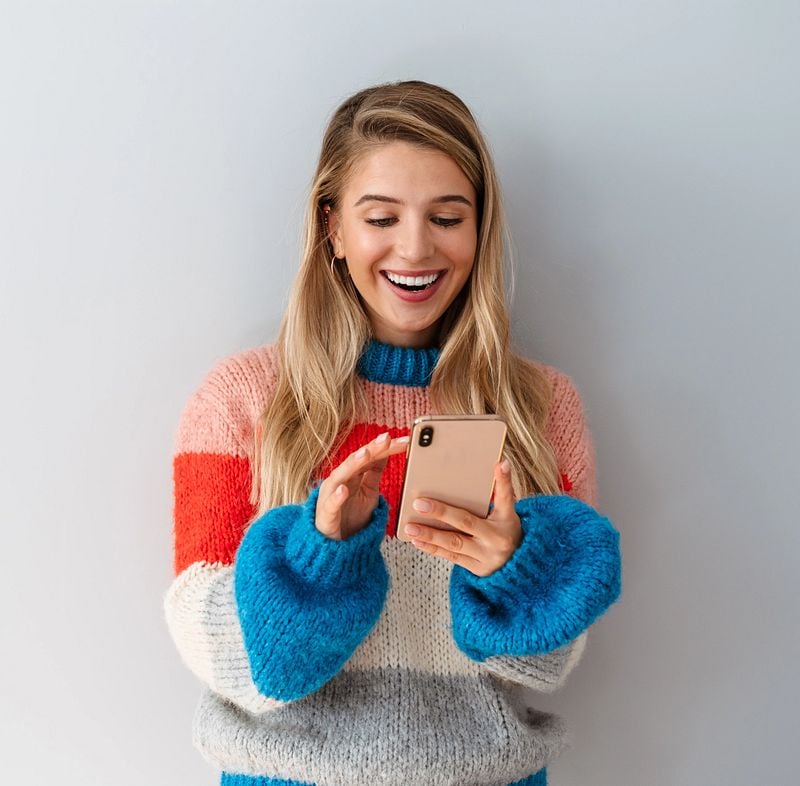 Eine Dame schaut glücklich überrascht auf Handy.