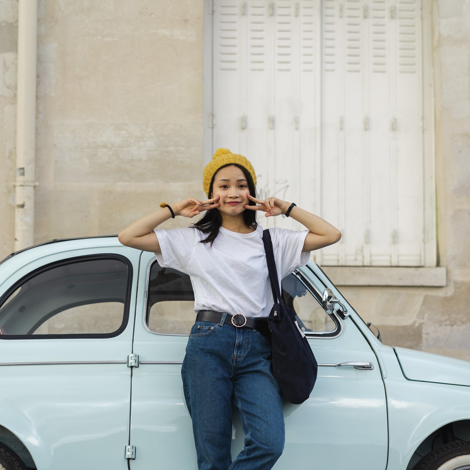 Junge Frau steht fröhlich vor ihrem Auto